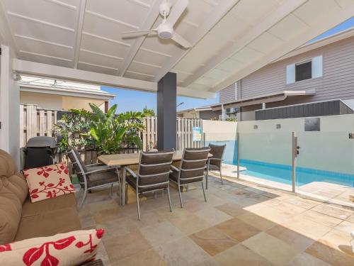 a patio with a table and chairs and a pool at Casuarina Dreaming Townhouse with Pool in Kingscliff