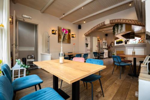 uma sala de jantar com uma mesa de madeira e cadeiras azuis em De Zonnetuin em De Haan