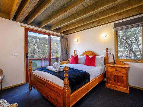 1 dormitorio con cama de madera y almohadas rojas en Banjo Apartments en Thredbo