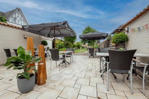 a patio with tables and chairs and umbrellas at De Zonnetuin in De Haan