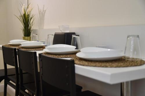 a table with chairs and white plates on it at Pompei Luxury Suite in Pompei