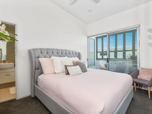 a bedroom with a large white bed with pink pillows at COASTAL CHIC @ CASUARINA in Casuarina