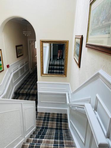 a hallway with a staircase with a mirror on the wall at Beechwood Ensuite Guest House in Ayr