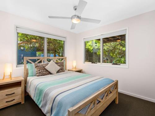 a bedroom with a bed and two windows at Casuarina Beach Shacks 10 with Pool in Kingscliff