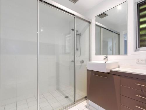 a bathroom with a glass shower and a sink at Casuarina Beach Shacks 10 with Pool in Kingscliff