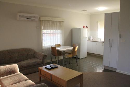 - un salon avec un canapé, une table et un réfrigérateur dans l'établissement Murray River Resort, à Moama
