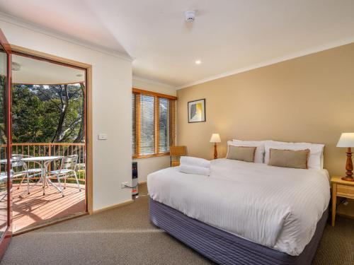 um quarto com uma cama grande e uma varanda em Lhotsky 2 Bedroom apartment with balcony mountain views and BBQ em Thredbo