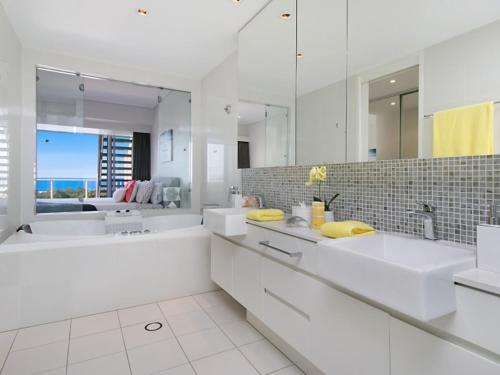 a white bathroom with two sinks and a mirror at 1328 Luxury Beachfront Penthouse with Heated Rooftop Jacuzzi in Kingscliff