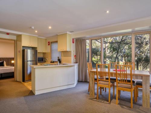 a kitchen and dining room with a table and chairs at Lhotsky 1 Bedroom apartment with tranquil outlook and onsite parking in Thredbo