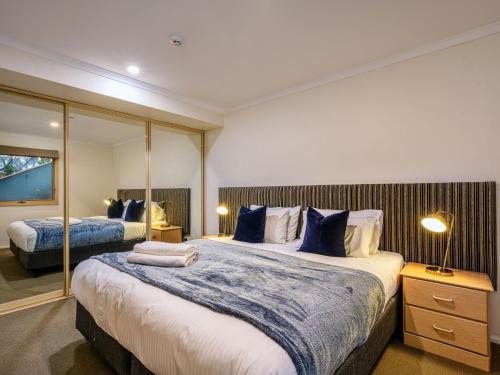 a bedroom with two beds and a mirror at Lhotsky 1 Bedroom apartment with tranquil outlook and onsite parking in Thredbo