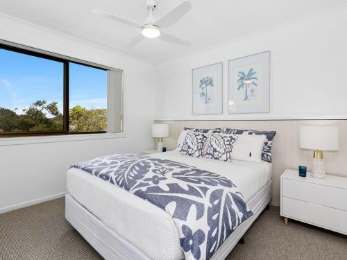 a white bedroom with a bed and a window at Shoreline 6 with Ocean Views To See The Whales in Hastings Point