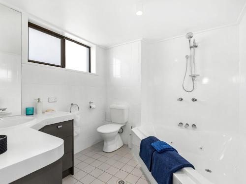 a white bathroom with a tub and a toilet and a sink at Shoreline 6 with Ocean Views To See The Whales in Hastings Point