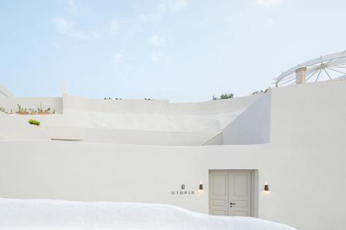 two views of a white building with a door at Utopia Suites Santorini in Karterados