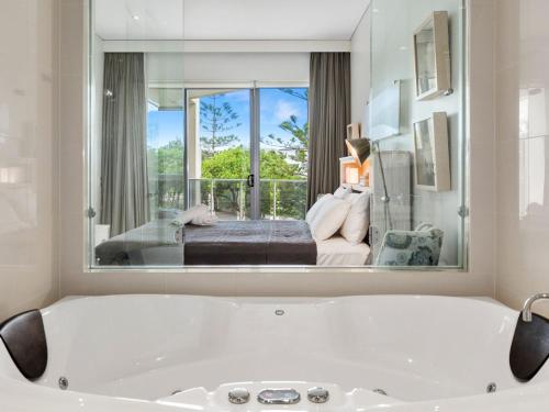 uma banheira branca numa sala com um quarto em Sea Culture 1110 Apartment with complex Pool & Spa em Kingscliff