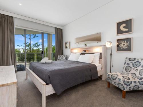 um quarto com uma cama, uma cadeira e uma janela em Sea Culture 1110 Apartment with complex Pool & Spa em Kingscliff