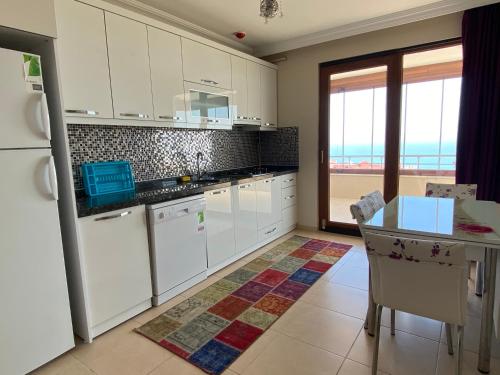 eine Küche mit weißen Geräten und einem Tisch mit Aussicht in der Unterkunft Ozgurcan Apart & Hotel in Trabzon