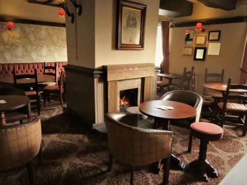 a restaurant with a fireplace and tables and chairs at The Roebuck Inn in Chapel en le Frith