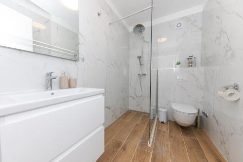 a white bathroom with a shower and a toilet at Enjoy Trogir Ciovo in Trogir