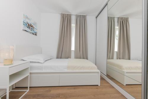 a white bedroom with a bed and a mirror at Enjoy Trogir Ciovo in Trogir
