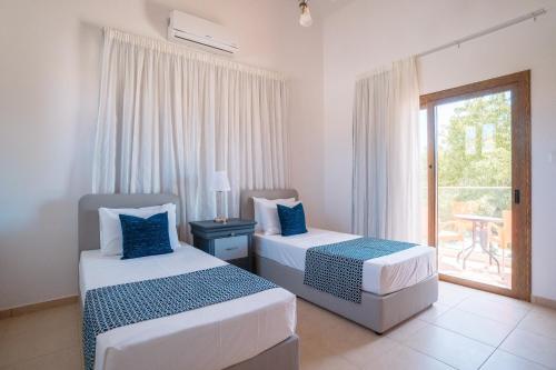 two beds in a room with a window at Andrea Villa by Prestige Bookings in Peyia