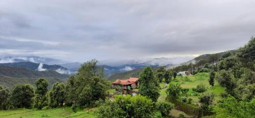 a house on a hill in a valley with trees at Maa Anand Mayee Guest House in Panuānaula