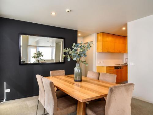 a dining room with a wooden table and a vase with flowers at Snow Stream 5 in Thredbo