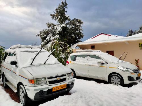 two cars parked in a driveway covered in snow at Maa Anand Mayee Guest House in Panuānaula
