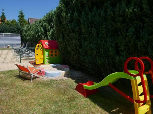 a playground with a slide and a chair in a yard at Ferienhäuser mit Pool in Rewal