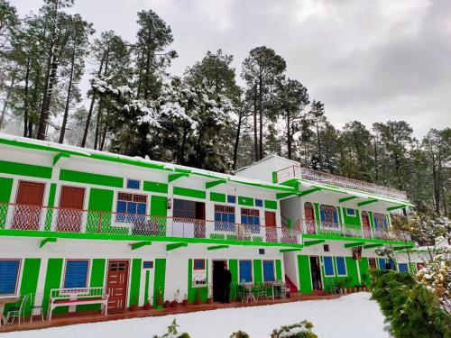 a building with green and white paint at Maa Anand Mayee Guest House in Panuānaula