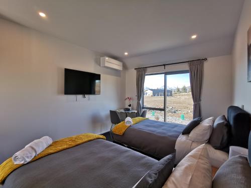 a living room with two beds and a flat screen tv at Skyrim Lodge in Lake Tekapo
