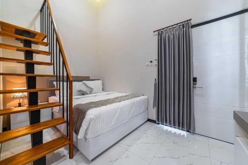 a small bedroom with a bed and a staircase at Tree Homestay Mitra RedDoorz in Kasri