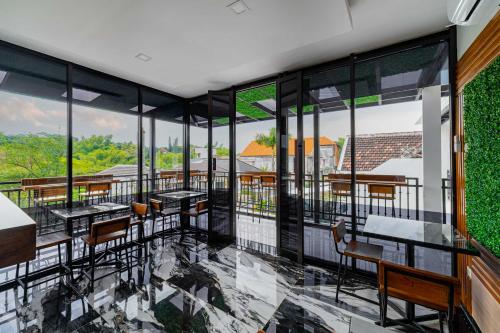 un ristorante con tavoli, sedie e finestre di Tree Homestay Mitra RedDoorz a Kasri