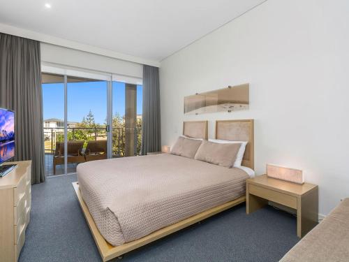 a bedroom with a large bed and a television at Coast Culture 1208 Apartment with complex Pool & Spa in Kingscliff