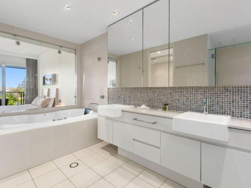 a white bathroom with two sinks and a bath tub at Coast Culture 1208 Apartment with complex Pool & Spa in Kingscliff