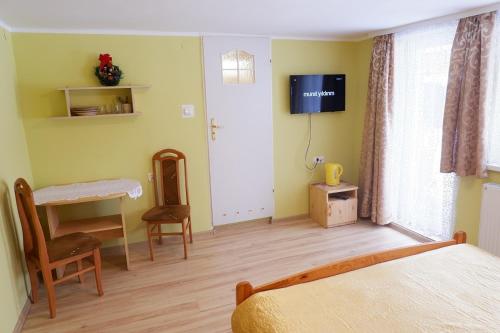 a bedroom with a bed and a table and a television at Pokoje Gościnne "Adam" in Ustroń