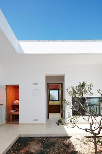 a white house with a tree in the courtyard at Villa The Longhouse- Pool-Sauna-Gym- Panormaic Seaview in Sellía