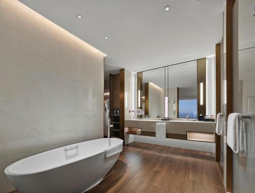 a bathroom with a white tub and a large mirror at Hyatt Regency Shanghai Songjiang in Songjiang