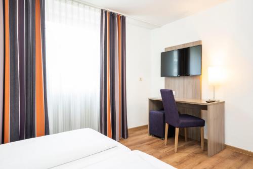 a hotel room with a desk and a tv at Bamberg Inn in Hallstadt
