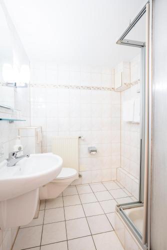 a white bathroom with a sink and a shower at Bamberg Inn in Hallstadt