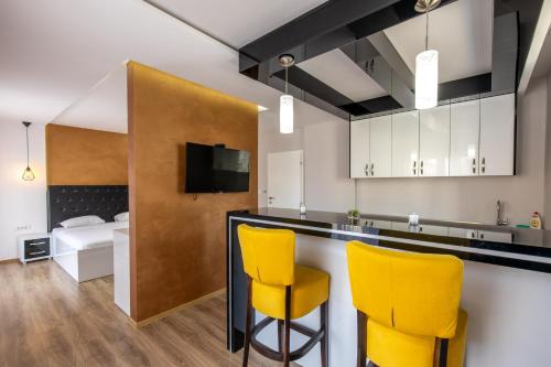 a kitchen with yellow chairs and a bar with a bed at Motel Milošević in Bijeljina