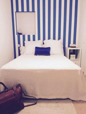 a bed with a blue and white striped wall at ALOJAMIENTOS DG in Punta Umbría