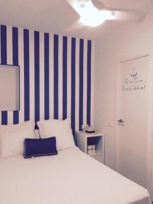 1 dormitorio con 1 cama con una pared de rayas azul y blanco en ALOJAMIENTOS DG, en Punta Umbría