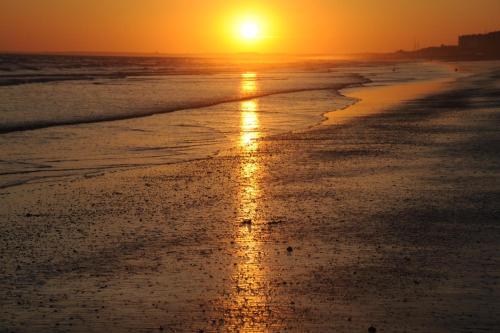 una puesta de sol en la playa con la marea entrando en ALOJAMIENTOS DG, en Punta Umbría