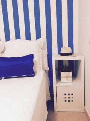 1 dormitorio con una pared de rayas azul y blanco en ALOJAMIENTOS DG, en Punta Umbría