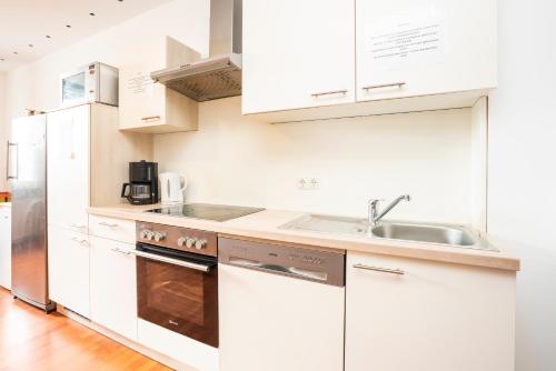 a white kitchen with white cabinets and a sink at Bamberg Inn in Hallstadt