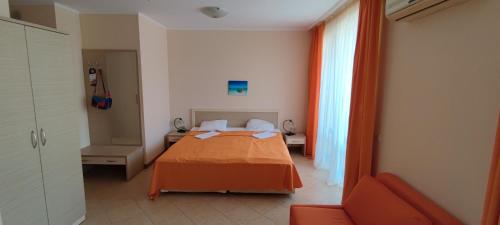 - une chambre avec un lit et une couverture orange dans l'établissement Holiday Apartcomplex Royal Sun, à Sunny Beach
