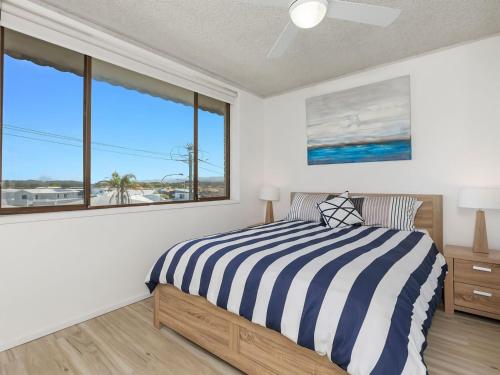 a bedroom with a bed and a large window at Kingy Beach Getaway with Balcony - Central Kingscliff in Kingscliff