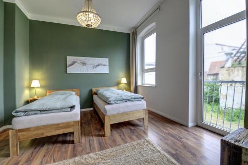 two beds in a room with green walls and windows at fewo1846 - Angelburg - komfortable Wohnung im Stadtzentrum in Flensburg