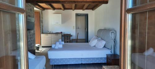 a bedroom with a white bed and a kitchen at Koukouri Suites in Areopolis
