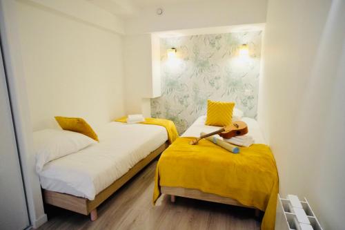 two beds in a small room with yellow sheets at City Affaire : Hotel de Ville in Caen
